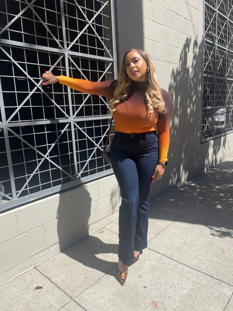 A petite woman wearing Joe's Jeans Provocateur petite flare jeans, paired with Jimmy Choo heels, Zara earrings, and a Ferragamo purse.