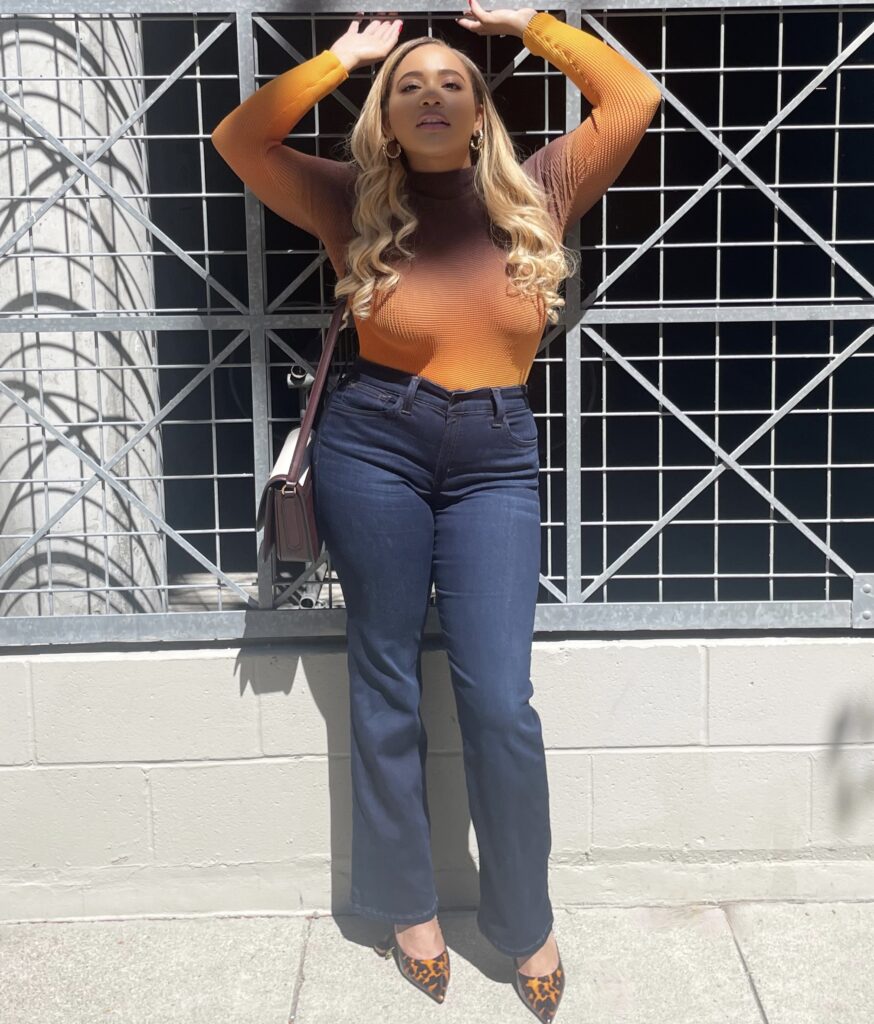 A petite woman wearing Joe's Jeans Provocateur petite flare jeans, paired with Jimmy Choo heels, Zara earrings, and a Ferragamo purse.